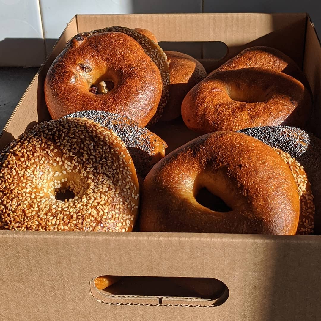 A cardboard box full of freshly baked bagels.