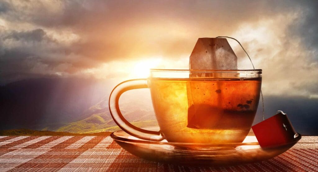 Image of tea bag infusing into glass mug with a sunset in the backdrop