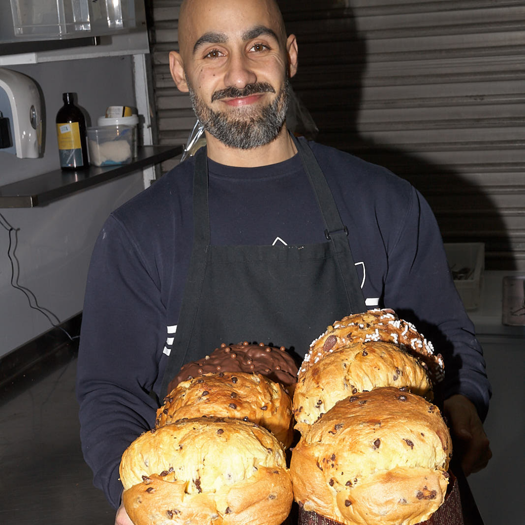 Man holding bread loaves in a kitchen setting.