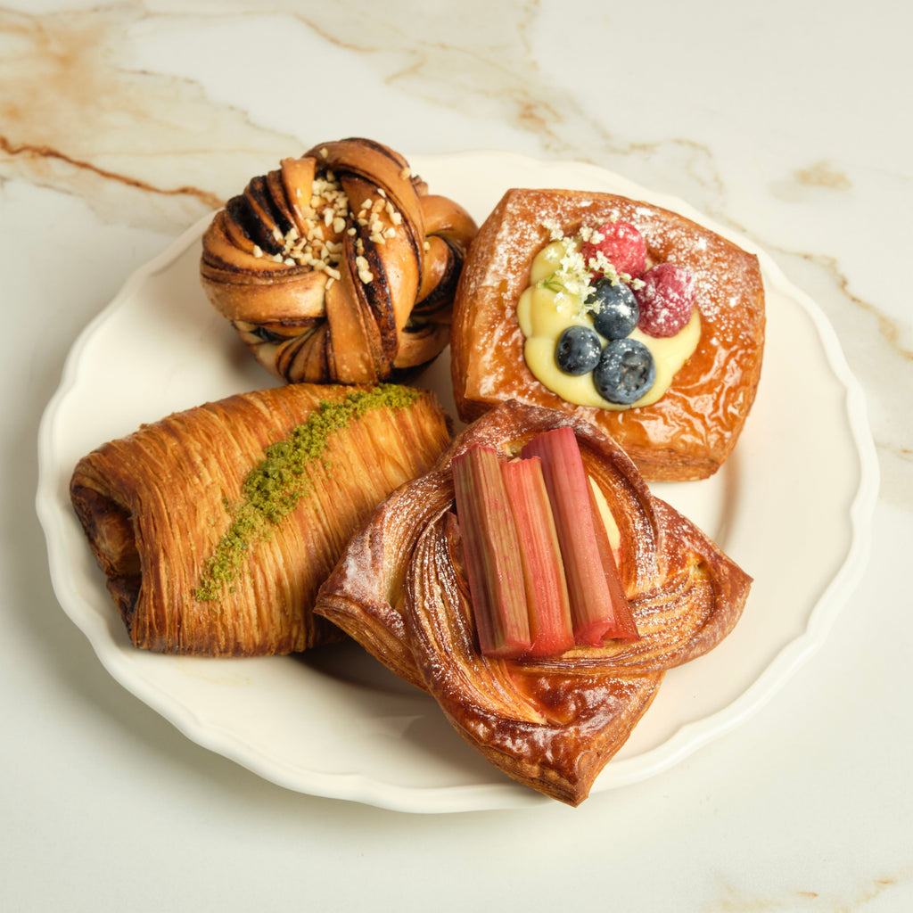 Four assorted pastries on a plate on top of a marble surface.