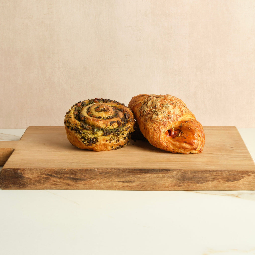 Two pastries on a wooden cutting board with a beige background.