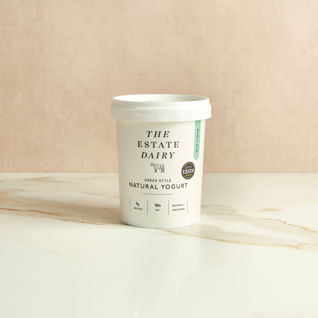 Container of The Estate Dairy greek style natural yogurt on a beige background.