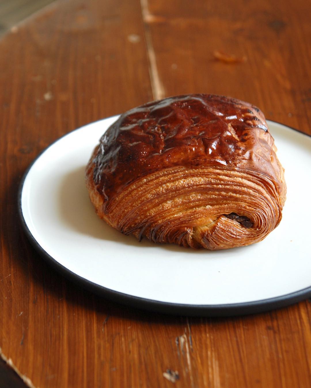 A freshly baked pan au chocolat on a white plate.