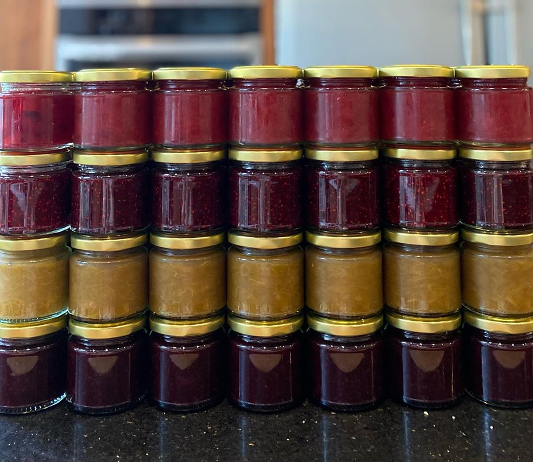 Stacked up glass jars of different coloured preserves.