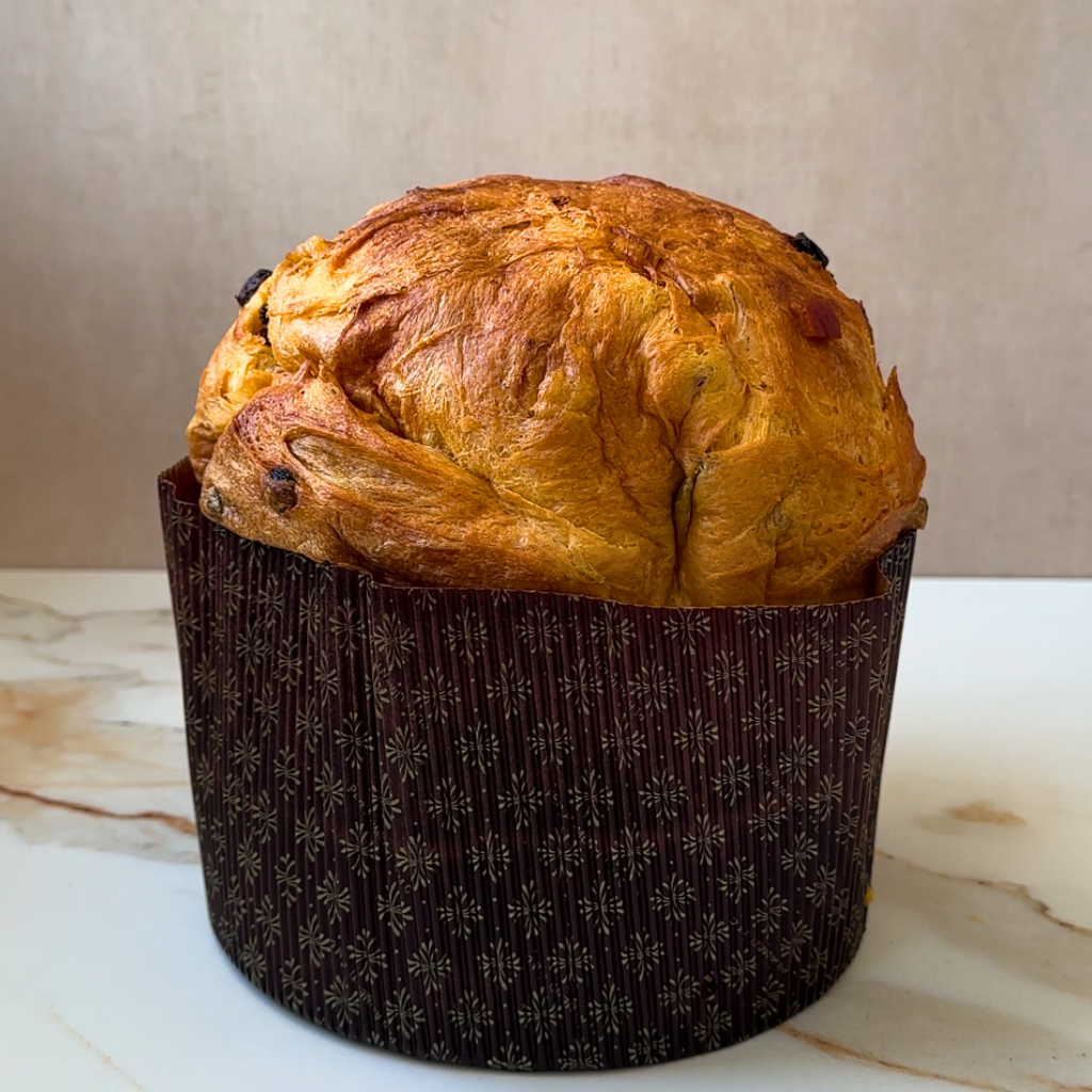 Panettone in brown paper lining on a marble surface.