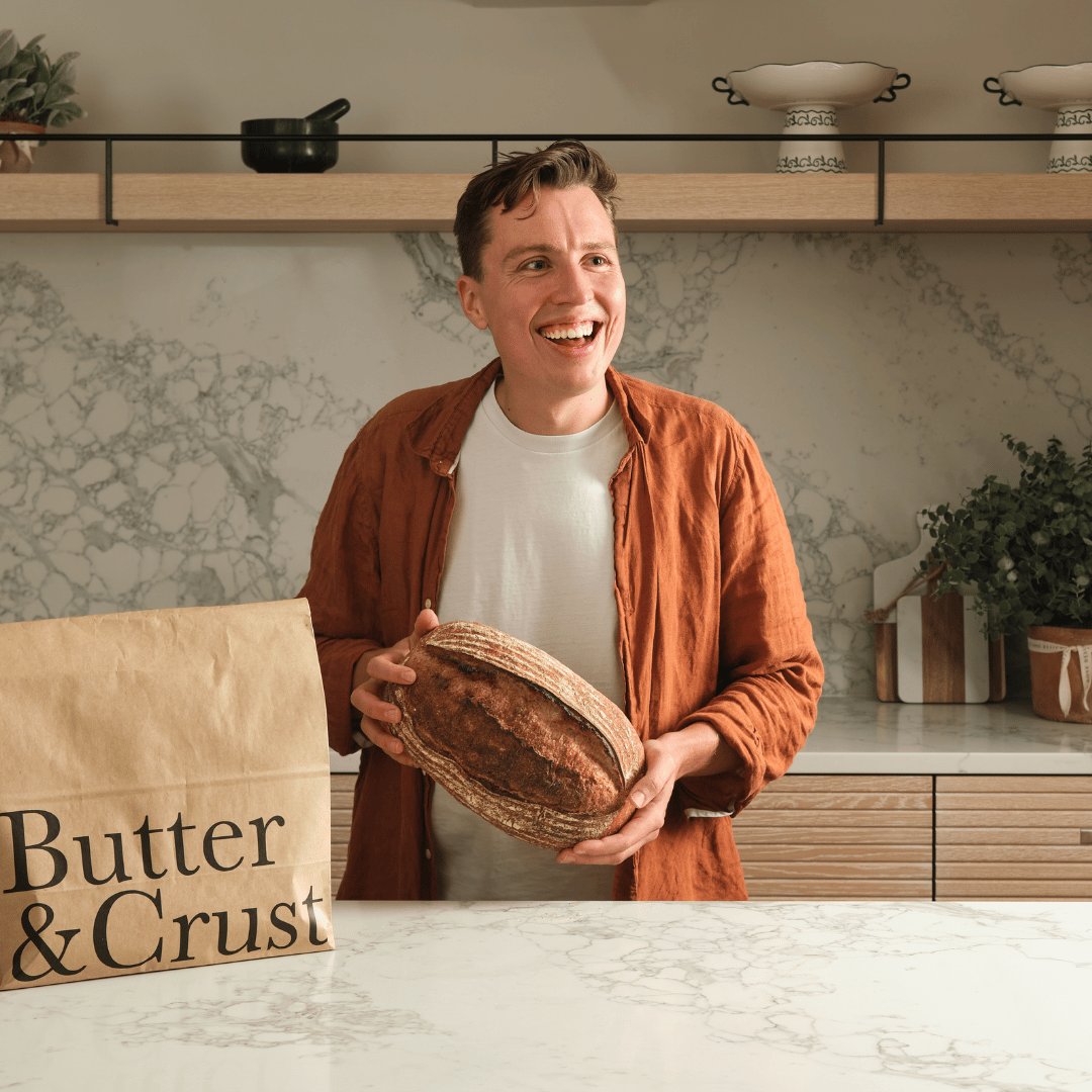 Ollie, founder of Butter and Crust, holding a sourdough loaf